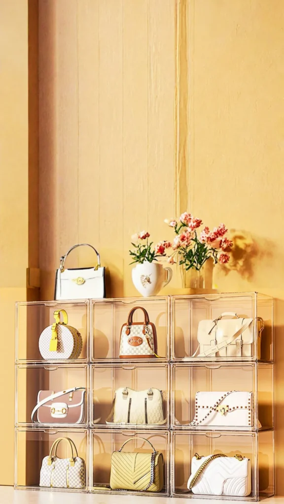 A stack of three elegant, decorative storage boxes with lids resting on a clean white shelf, creating a stylish closet display. The boxes feature a matching design with a smooth, light beige faux leather finish, accented by clean lines and minimal modern hardware. The top box is slightly open, revealing a glimpse of delicate items stored safely inside, blending organization with luxurious interior decor.