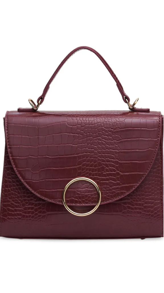 A structured maroon satchel handbag featuring an embossed crocodile texture. The bag has a curved front flap adorned with a prominent gold ring clasp closure, a single top handle attached with gold hardware, and is isolated against a clean white background.