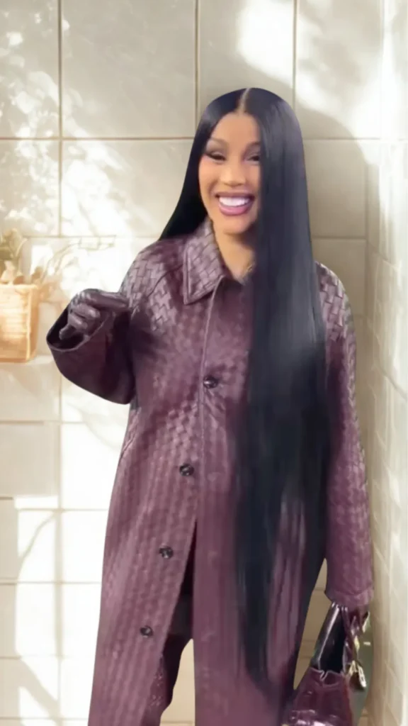 A woman with long, sleek black hair wearing a bold head-to-toe maroon monochrome outfit in 3.png. She is wearing an oversized woven leather jacket coat and matching dark leather gloves. She is smiling and carrying a structured maroon handbag with top handles, perfectly exemplifying how to break up a monochrome look with deep textures.