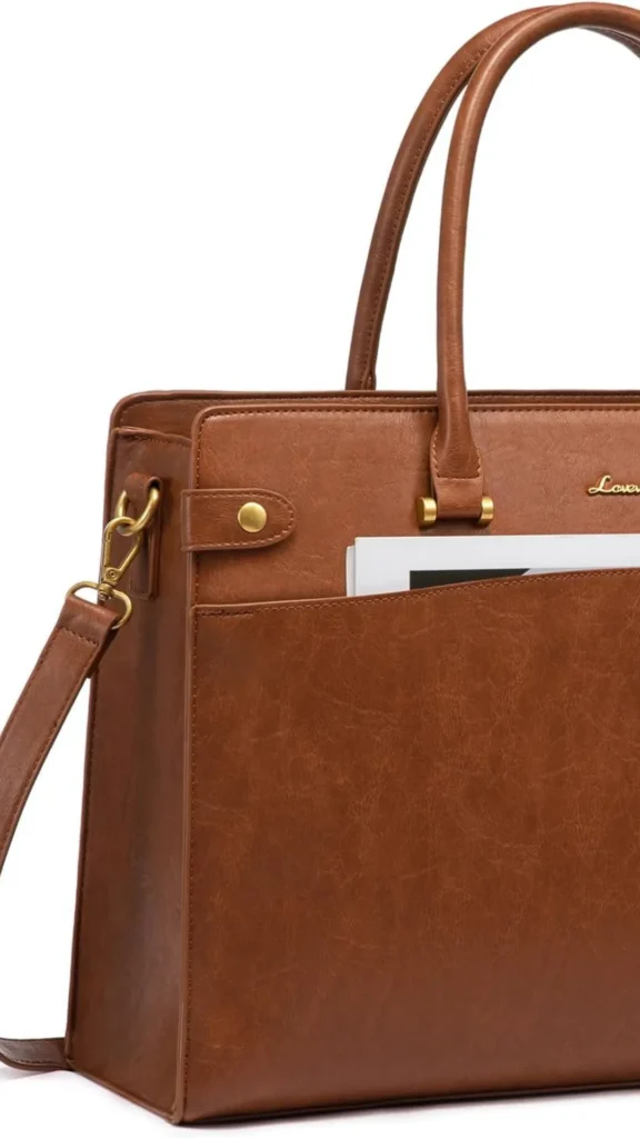 An image from file "3_22.webp" showing a close-up, angled view of a structured brown vegan leather laptop handbag against a plain white background. The tote showcases a textured marbling pattern across its surface and is equipped with rolled top handles attached via subtle gold metal hardware. A wide, horizontal front slip pocket holds white document papers, and a side decorative tab features a small gold snap button. The bag also includes a detachable matching brown shoulder strap fastened with a gold lobster clasp on the side.